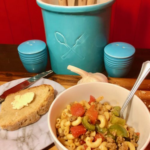 american chop suey new england style in a bowl with buttered bread on the side