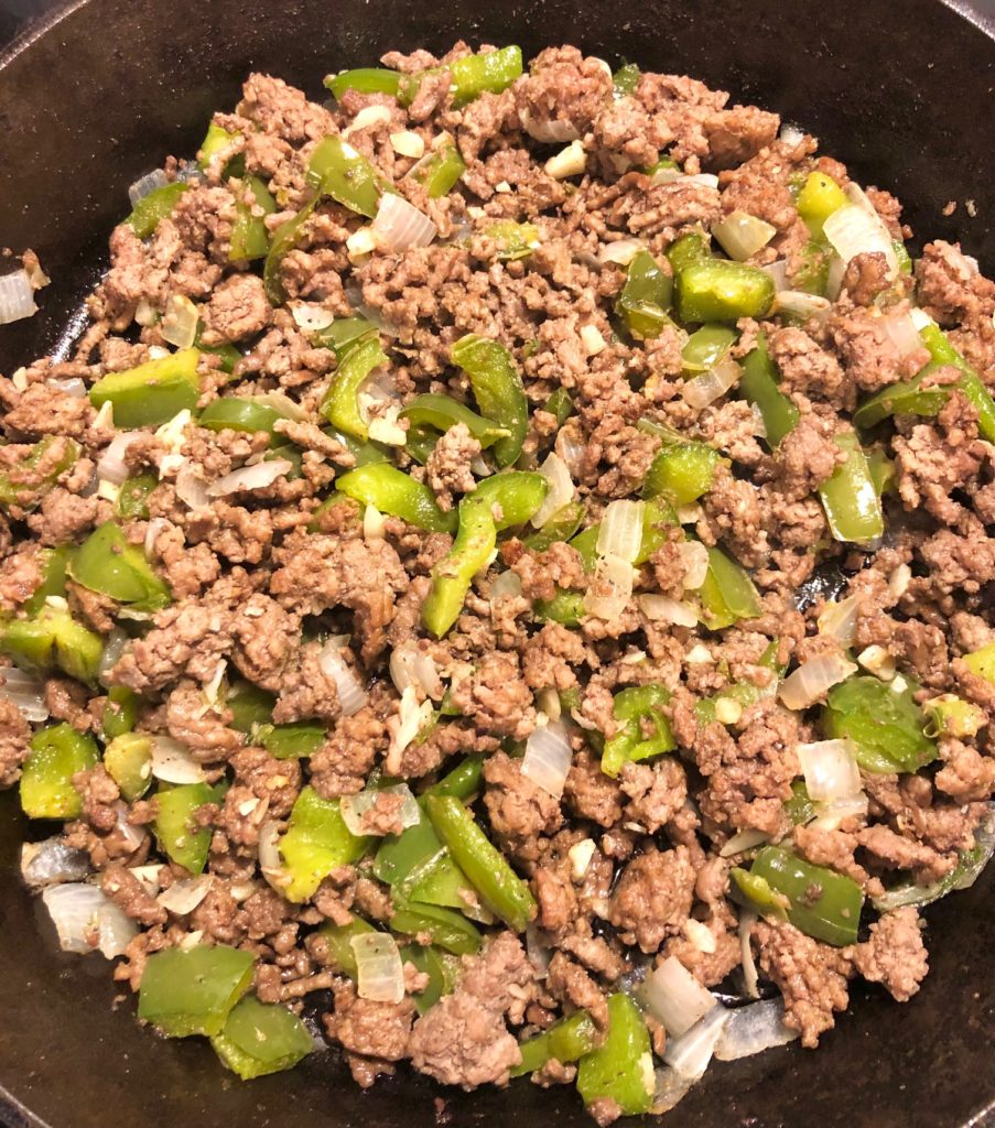 ground beef onion green pepper and garlic browning in cast iron skillet