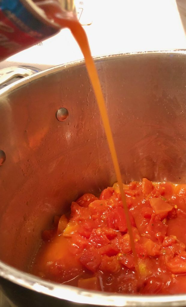 tomato juice being poured into pot with diced tomatoes