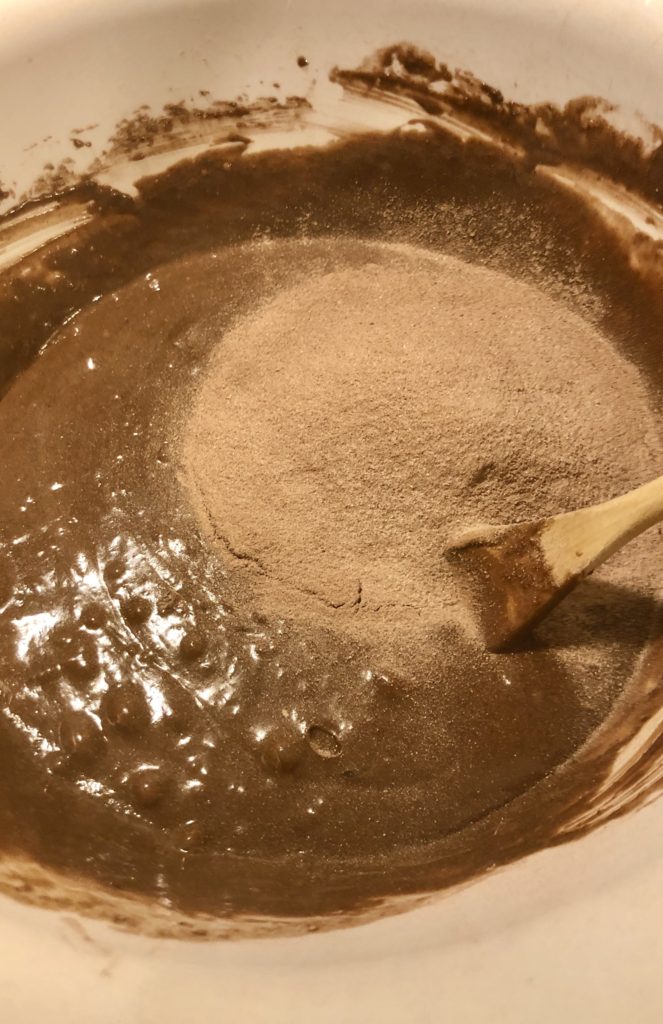prepared cake mix batter in large white mixing bowl with six packets of hot cocoa mix added
