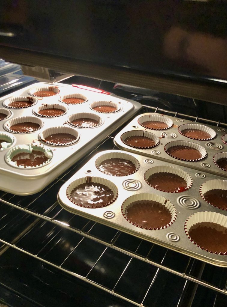 hot cocoa cupcake batter in muffin tins in the oven to bake