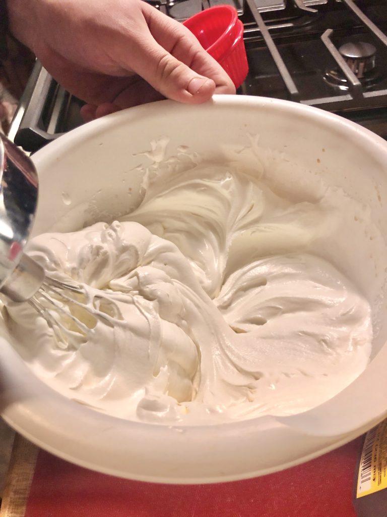 medium white mixing bowl with marshmallow frosting having cool whip whipped together