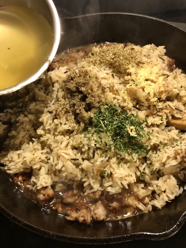 wild rice and sausage stuffing with herbs and chicken broth added to skillet