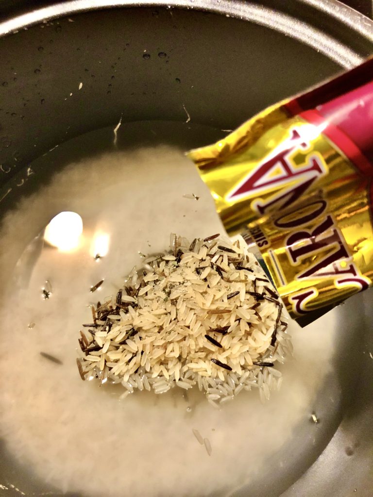 white rice in rice pot with Carolina wild rice packet being added