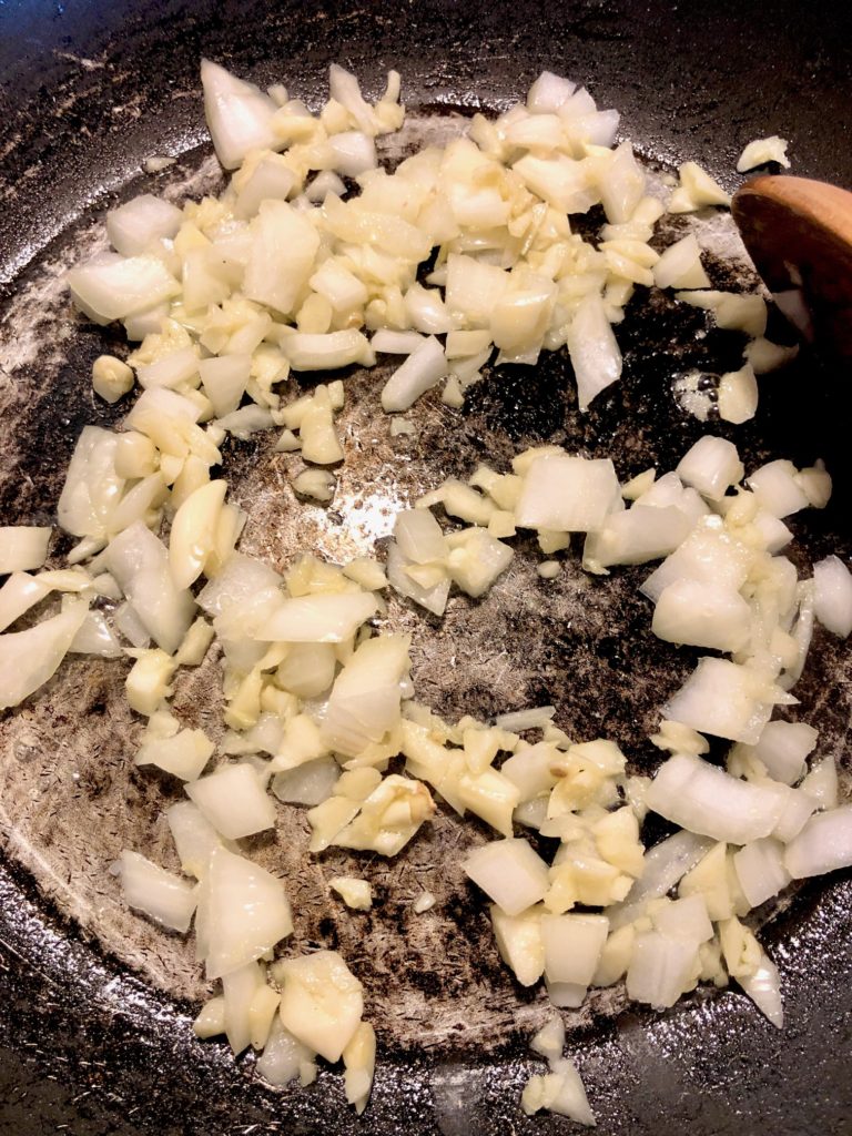 garlic and onion cooking in cast iron skillet