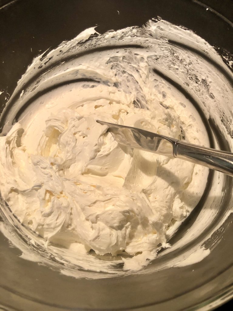 cream cheese and cool whip frosting beaten together in glass bowl
