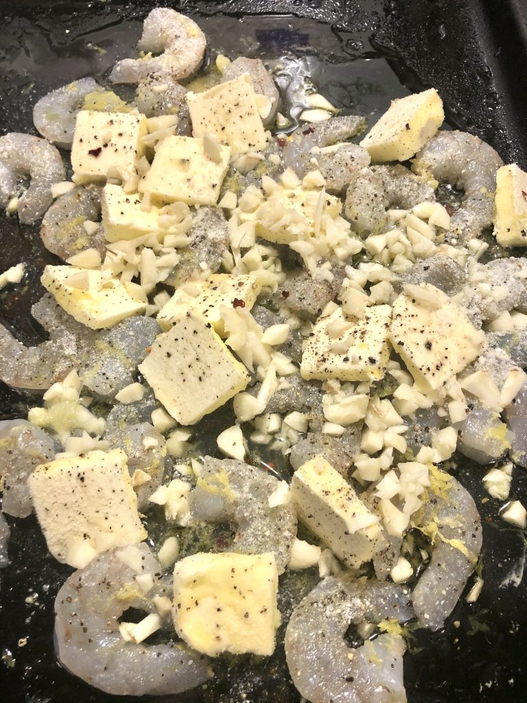 Prepped baking pan for shrimp scampi with shrimp, butter, lemon zest, etc.