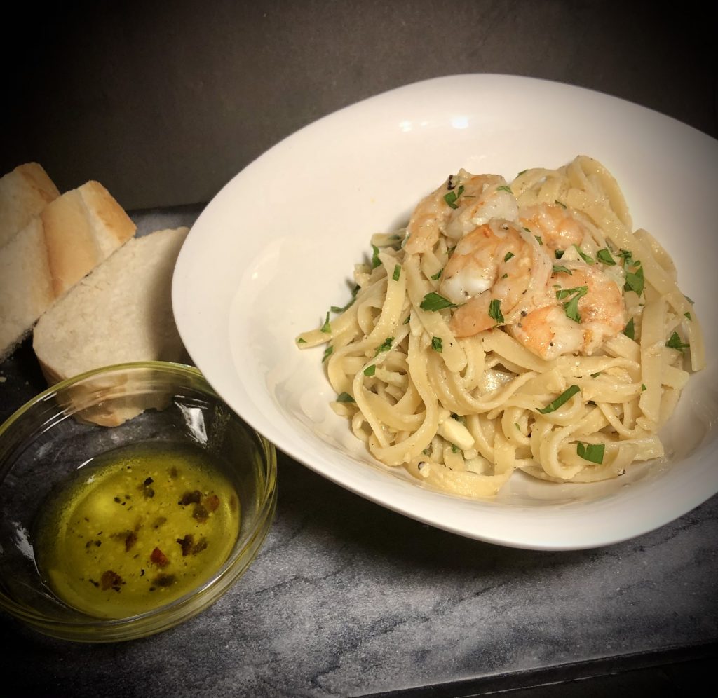 shrimp scampi on marble top with parisian bread and bread oil dip