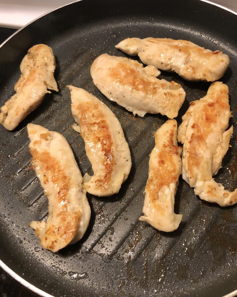 chicken tenderloins frying in black grill pan