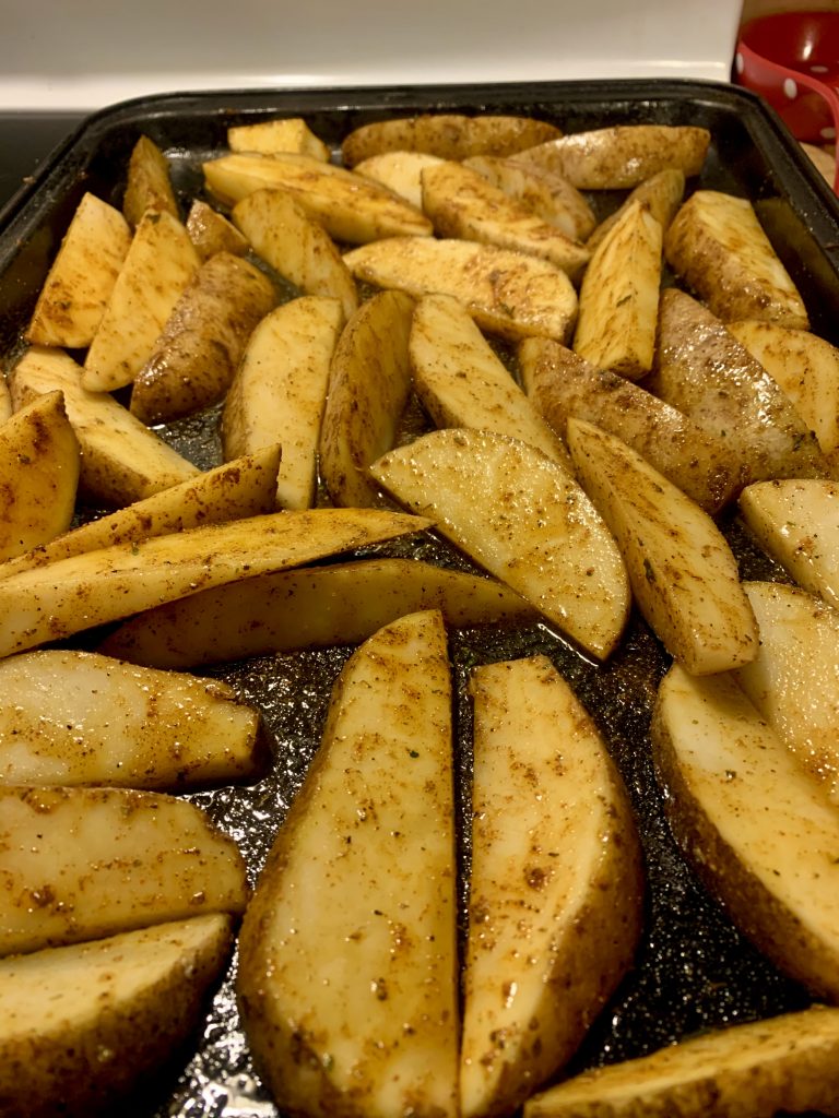 spicy potato wedges seasoned in pan before baking