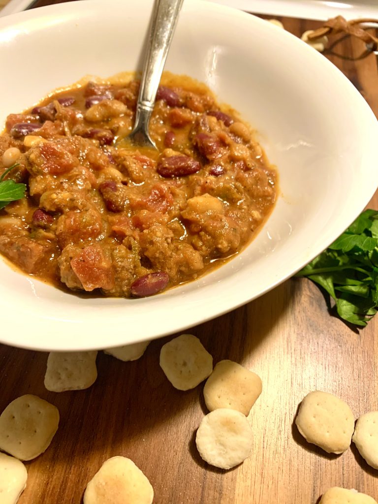 side shot of 5-alarm chili in white bowl on cutting board with oyster crackers