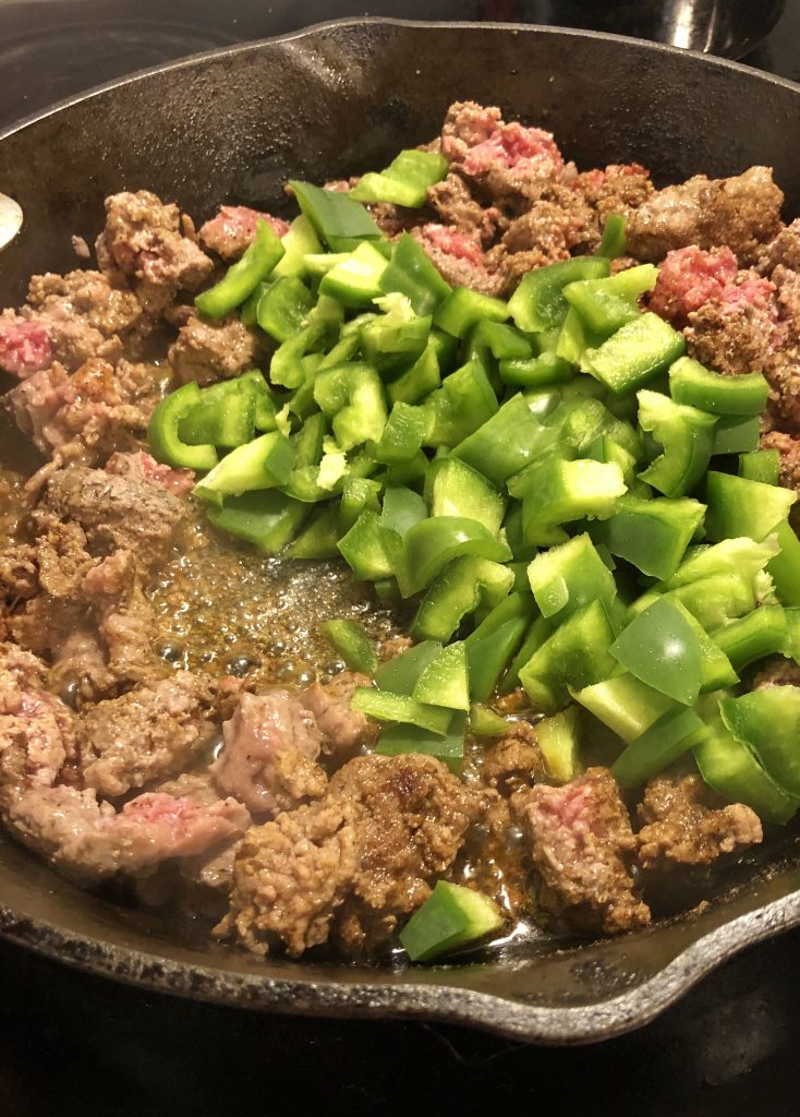 hamburger frying pan with fresh cut green peppers