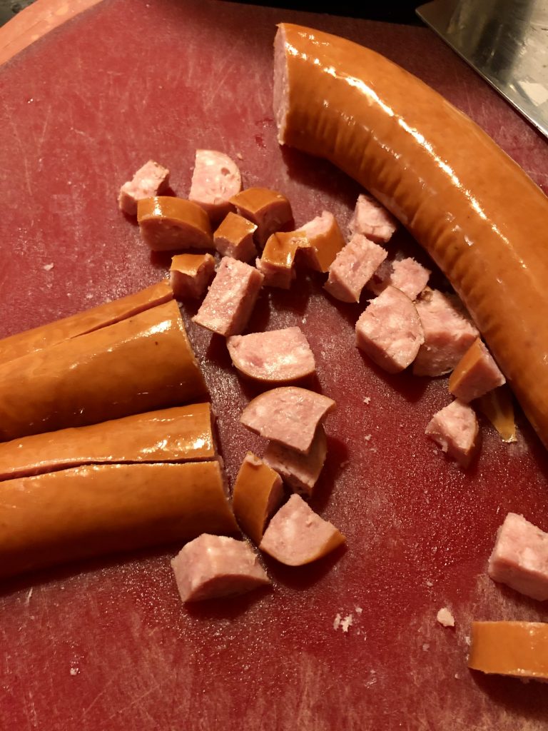 sliced kielbasa chunks on red cutting board