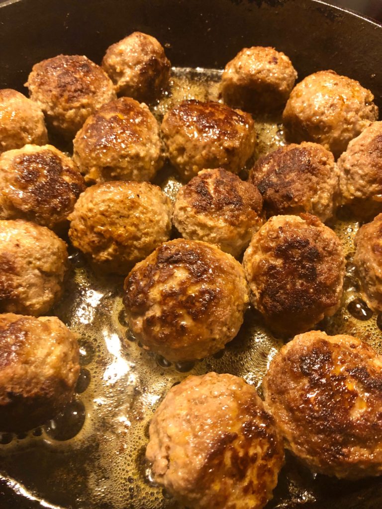 Korean meatballs being fried in cast iron skillet