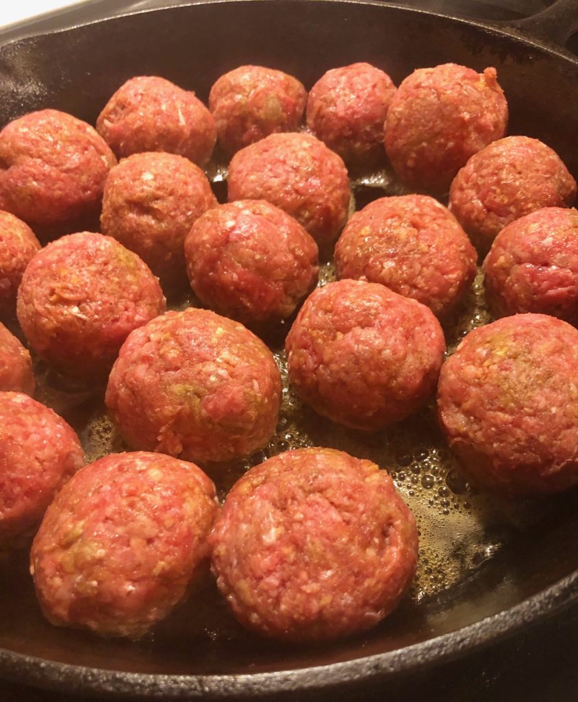 meatballs added to cast iron skillet for frying