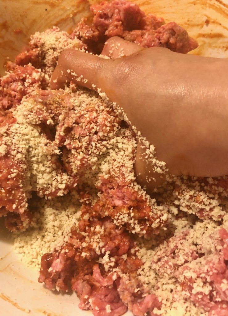 mixing meatballs by hand in large mixing bowl