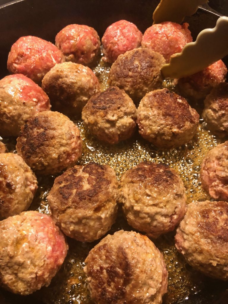 flipping frying meatballs in skillet