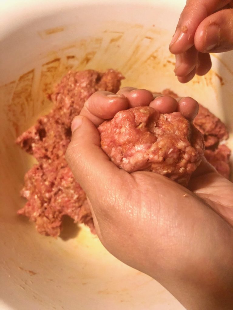 rolling Korean meatball from white mixing bowl