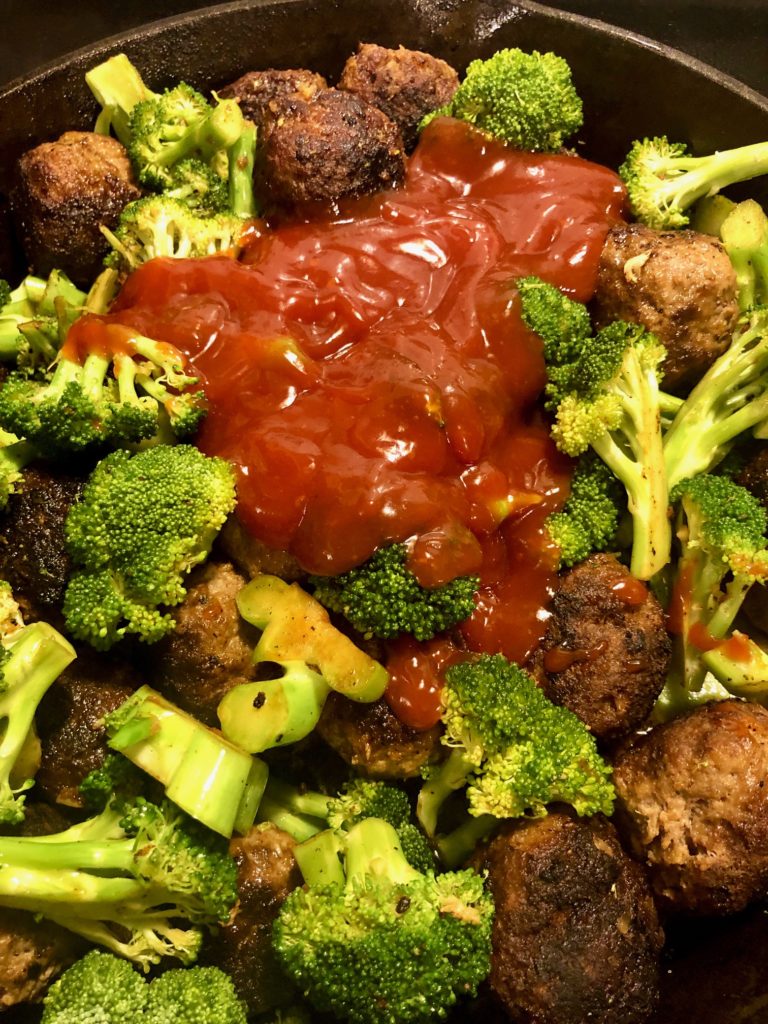 meatballs and broccoli frying in skillet with gochujang brown sugar ketchup sauce