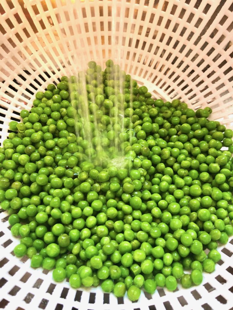 rinsing petite sweet peas in cold water in strainer