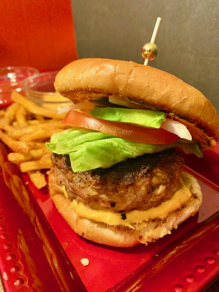 california turkey and sausage burFreger with sriracha mayo, lettuce, tomato, onion, jalapeno and avocado. It is served alongside cajun fries and two dipping sauces