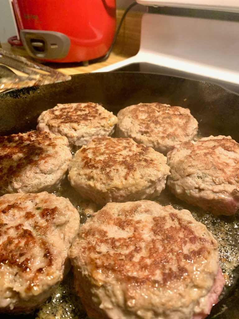 turkey sausage burgers frying in a skillet