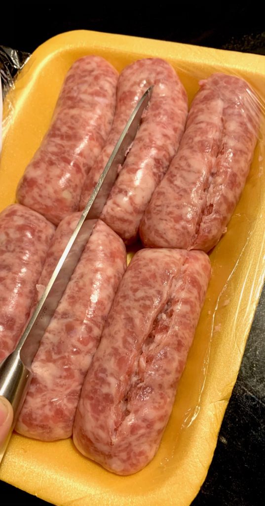 slicing sweet Italian sausage links in a package