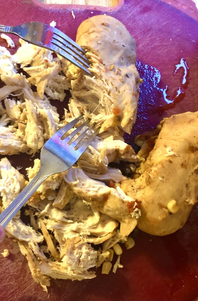 shredding mexican slow cooker chicken on cutting board with forks