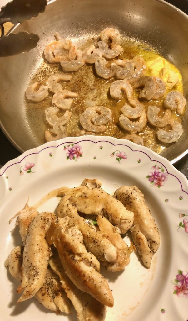 chicken tenderloin in floral bowl in front of shrimp frying in pan