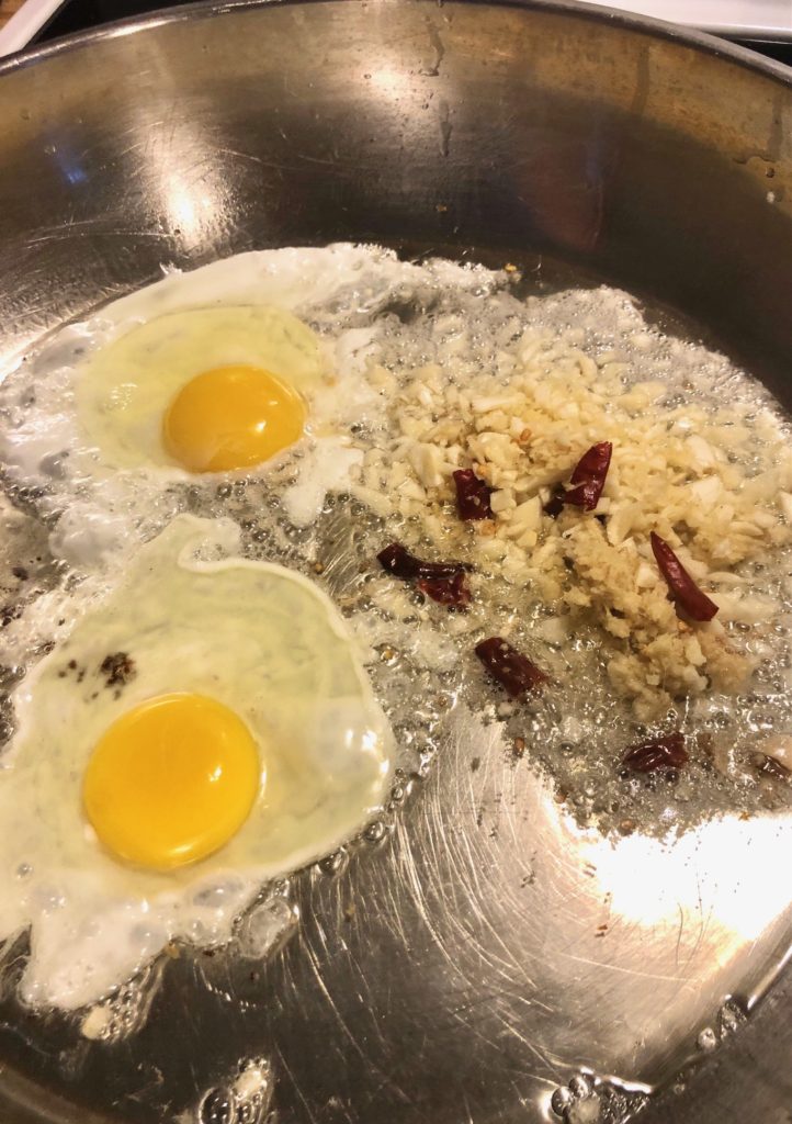 garlic, ginger, thai chilis and eggs frying in pan with vegetable oil