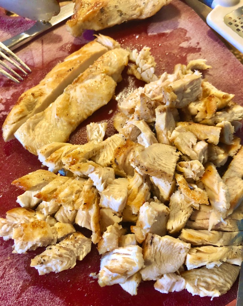slicing chicken tenderloins on red cutting board