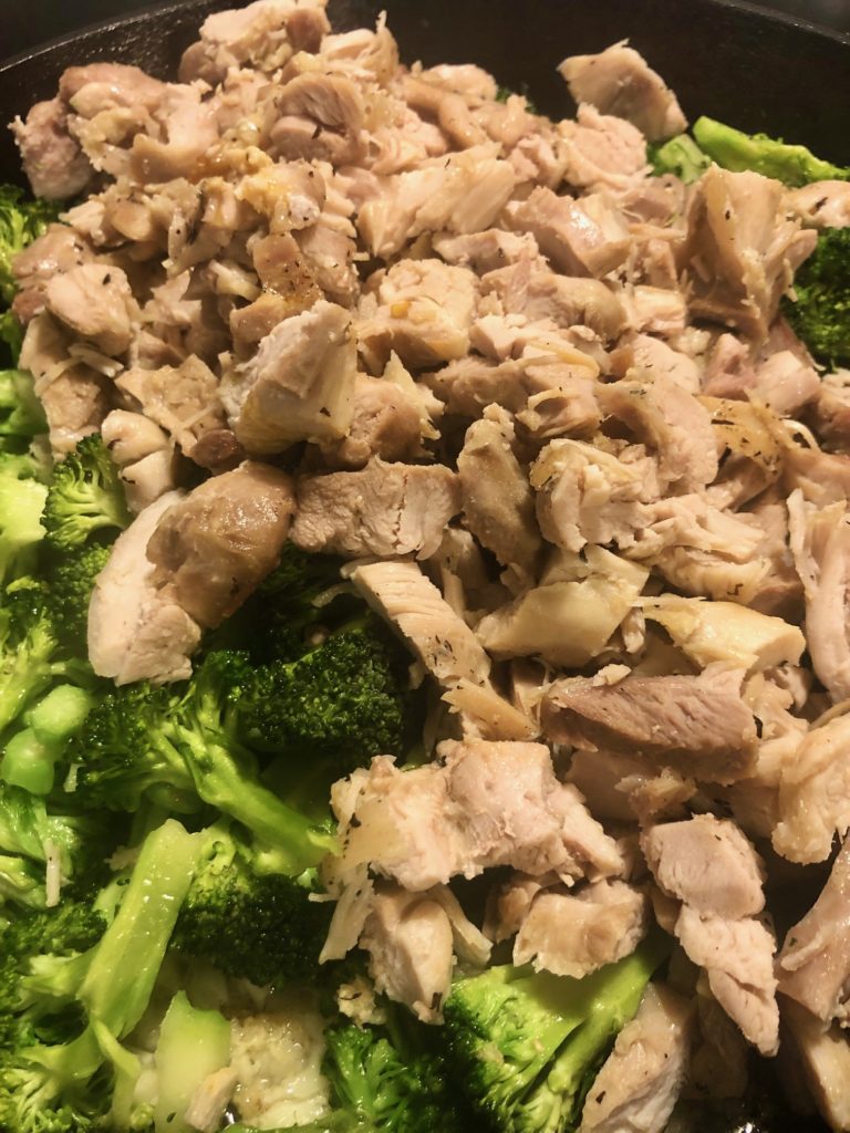 boneless skinless chicken breast added to broccoli in cast iron skillet