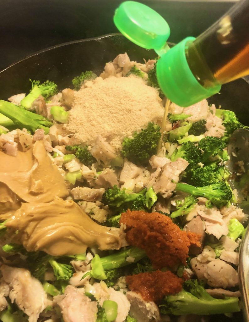peanut butter, brown sugar, red curry paste, garlic, ginger, broccoli and chicken in skillet with fish sauce being added