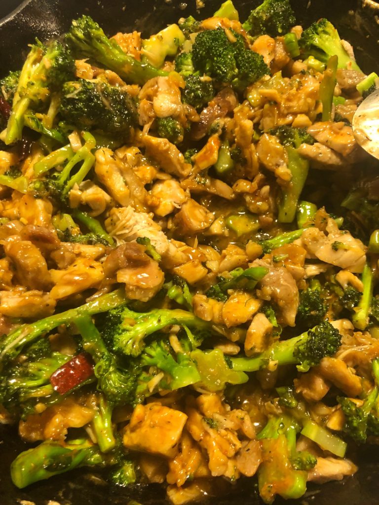 Thai peanut chicken with broccoli in cast iron skillet once the sauce has been mixed and the dish is coming together