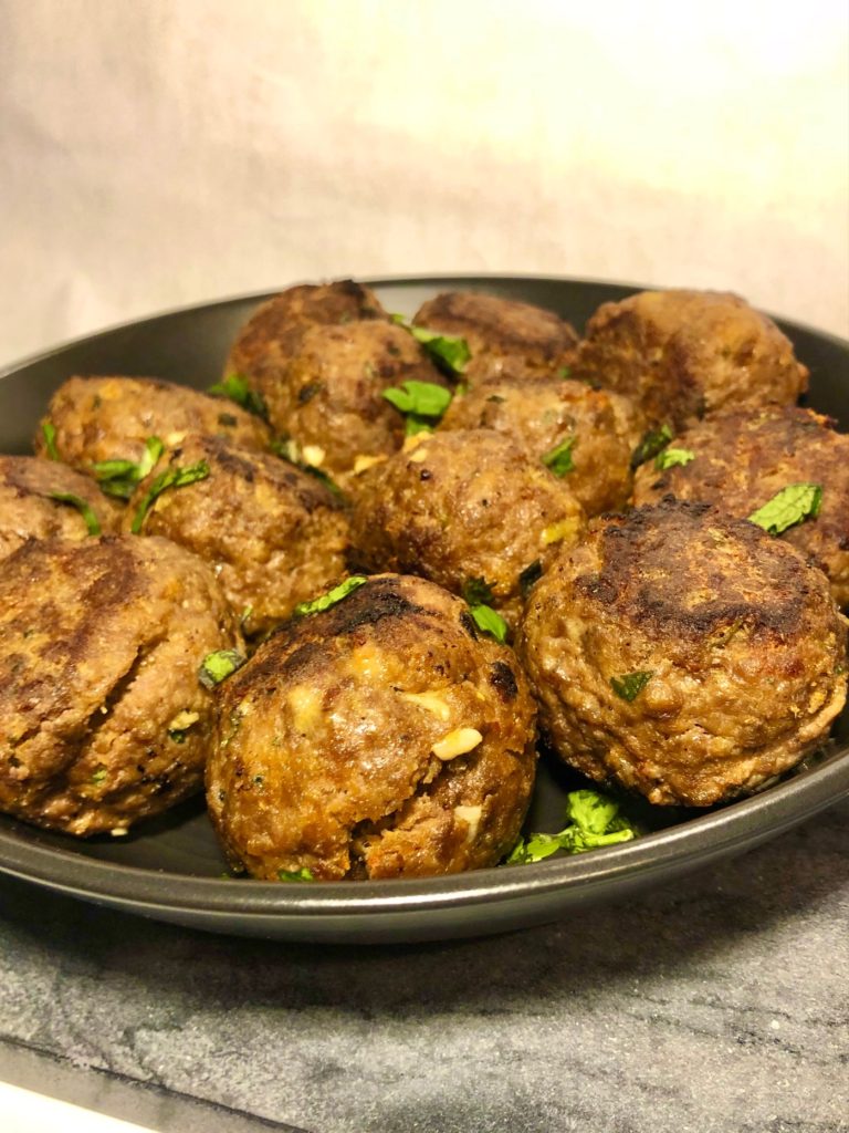 thai style meatballs plated on black matte plate and garnished with cilantro