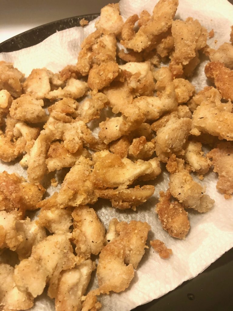fried sliced breaded chicken on paper towel lined plate