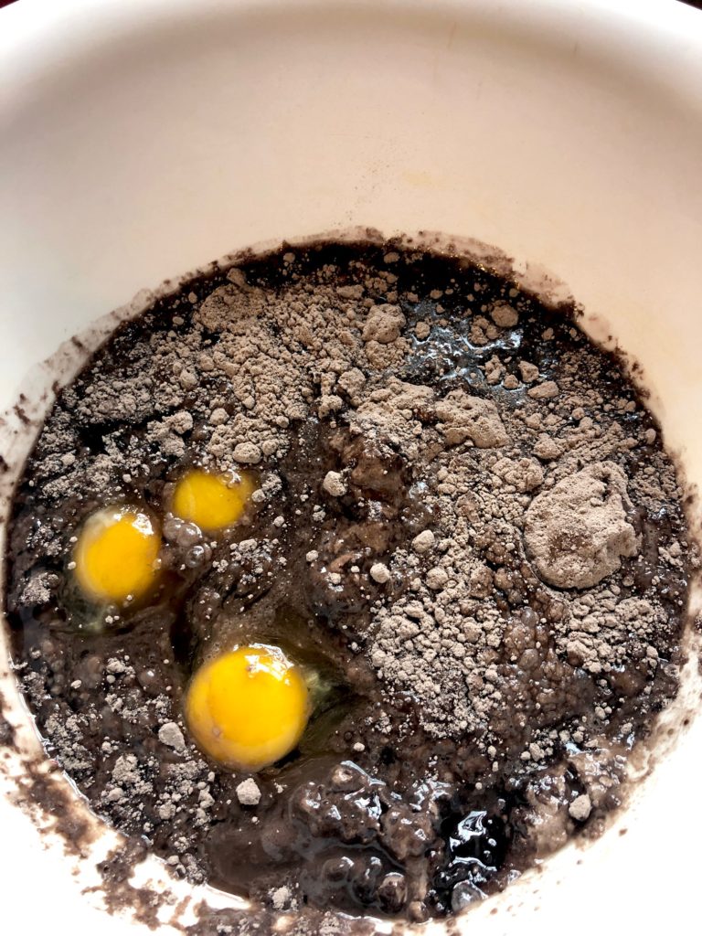 dark chocolate box cake mix being prepared in white mixing bowl. The bowl includes water, vegetable oil and eggs