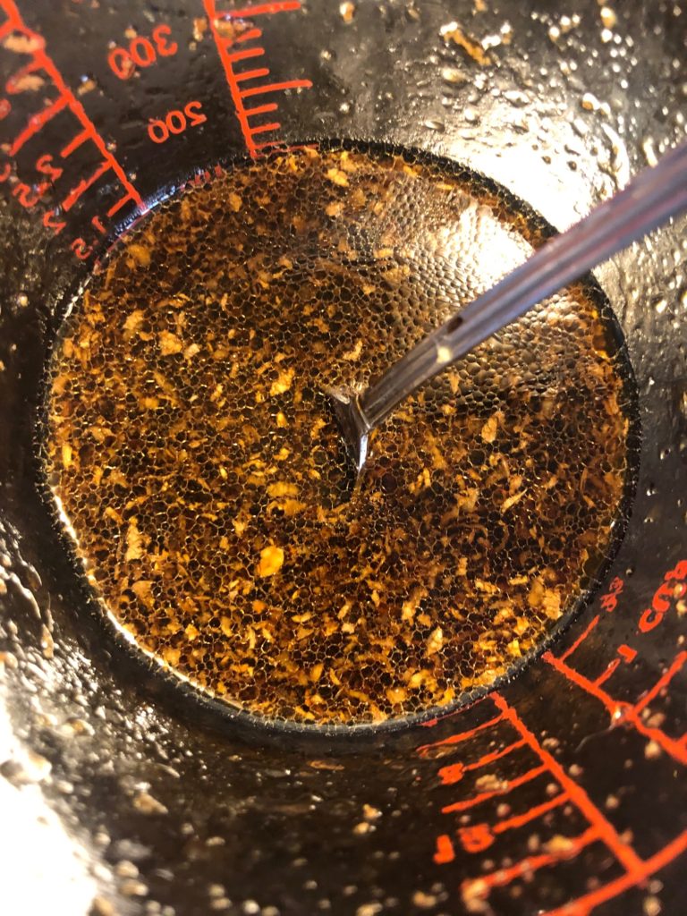 soy sauce marinade with grated ginger in glass measuring glass with silver mixing spoon