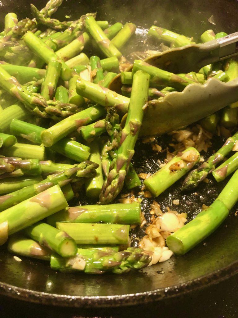 asparagus garlic and thai chilis cooking in black pan