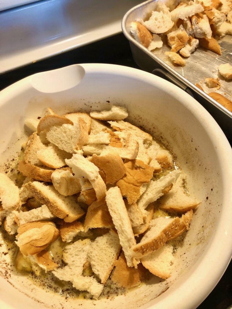 day old torn bread added to french toast egg mixture in large white mixing bowl