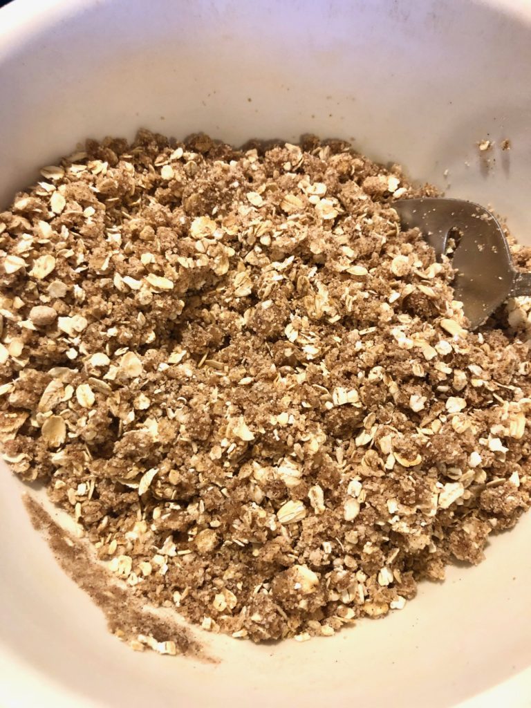 oats, flour, sugar, brown sugar, cinnamon and salt crumb topping moistened with vegetable oil in white mixing bowl