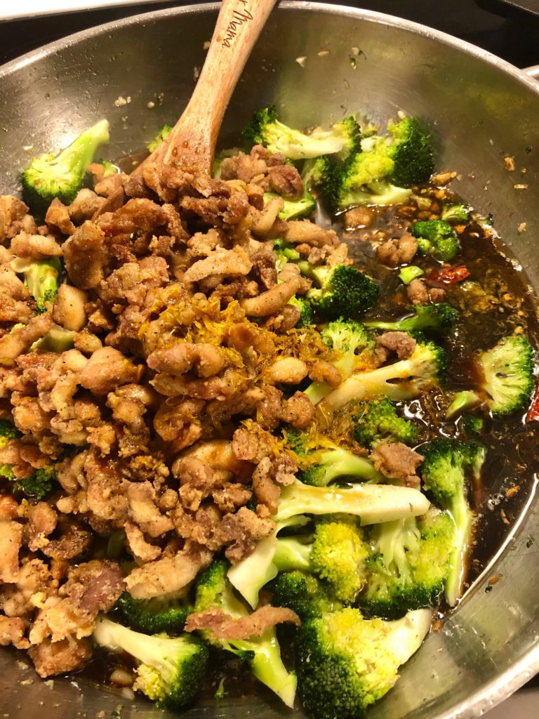 boneless skinless chicken frying with broccoli and Thai chilis in an orange sauce