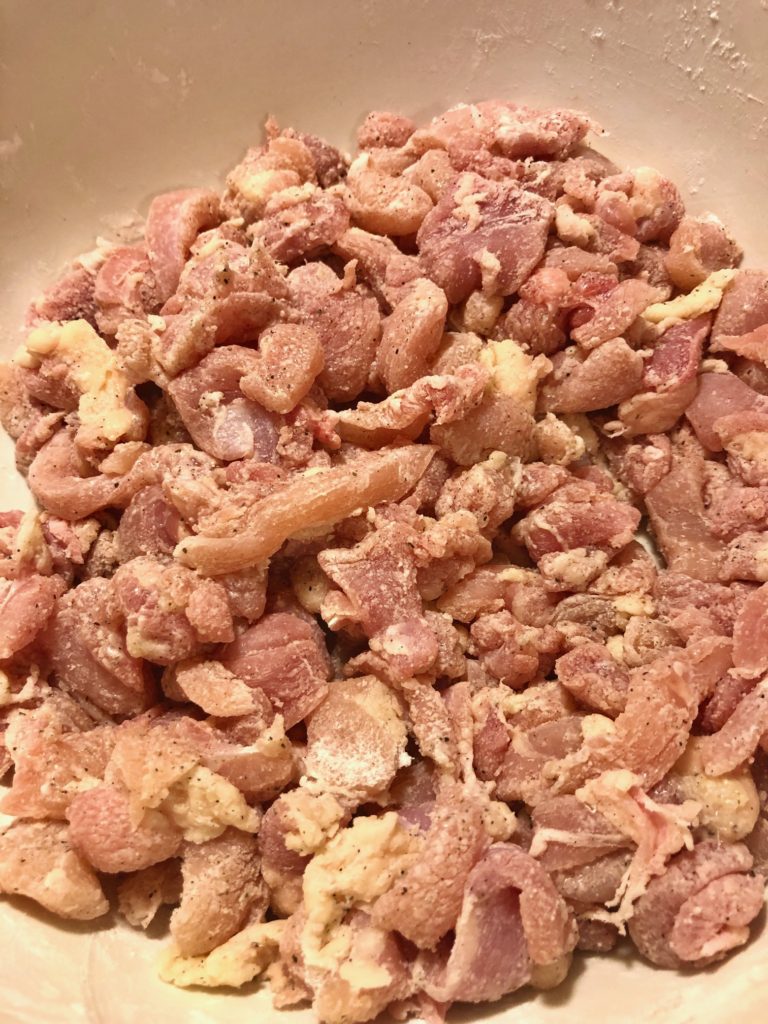 boneless skinless chicken in mixing bowl with cornstarch, salt and black pepper