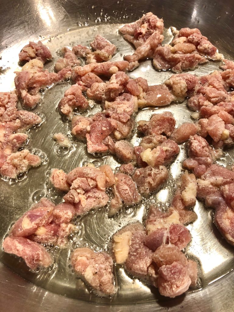 cornstarch coated boneless skinless chicken frying in pan