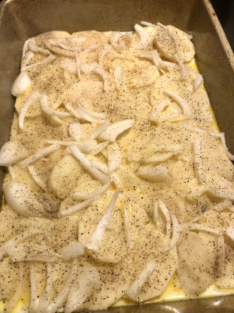 thinly sliced potatoes layer with salt, black pepper, onion, milk and butter mix