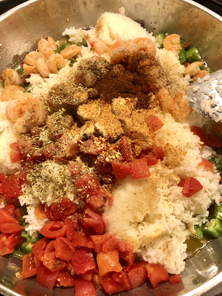 rice, kielbasa, shrimp, green pepper, okra and diced tomatoes in skillet. seasonings over the top of cumin, chili pepper, creole seasoning, garlic powder, salt and black pepper