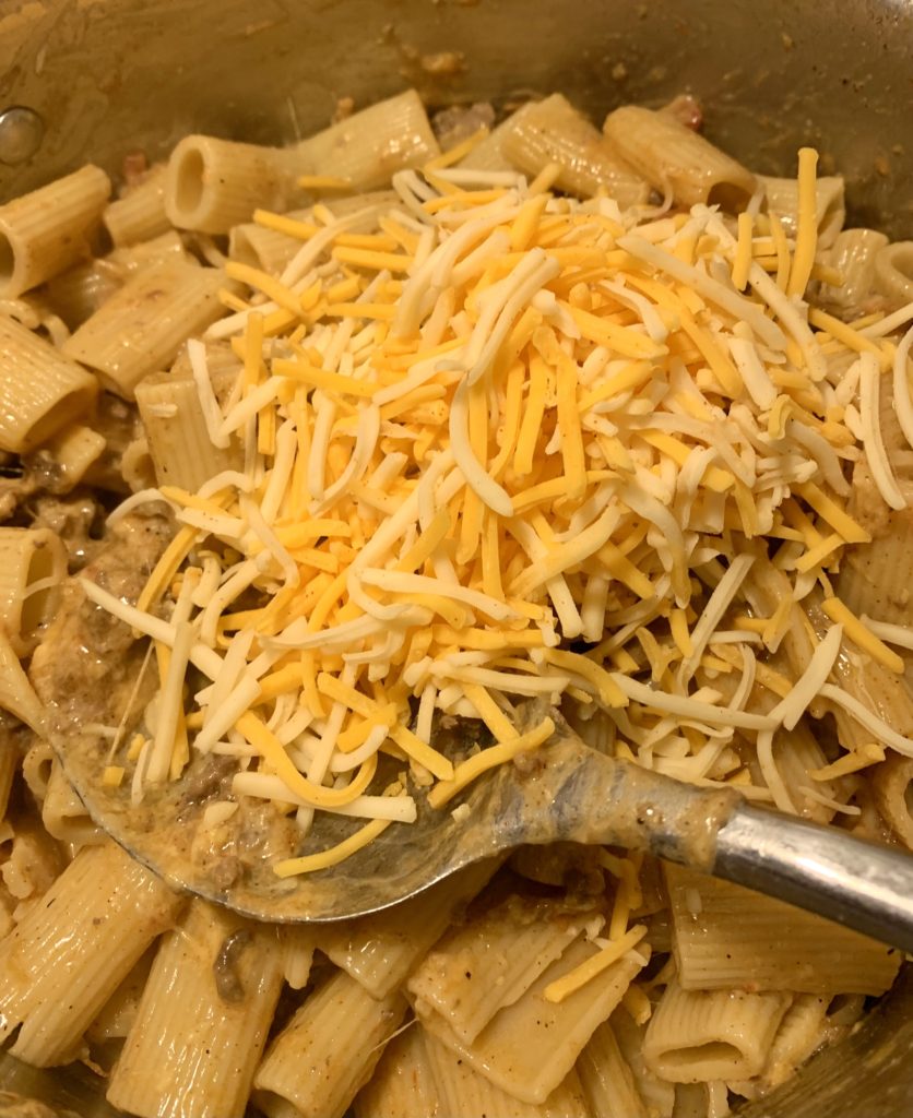 taco pasta with additional taco cheese being added and stirred