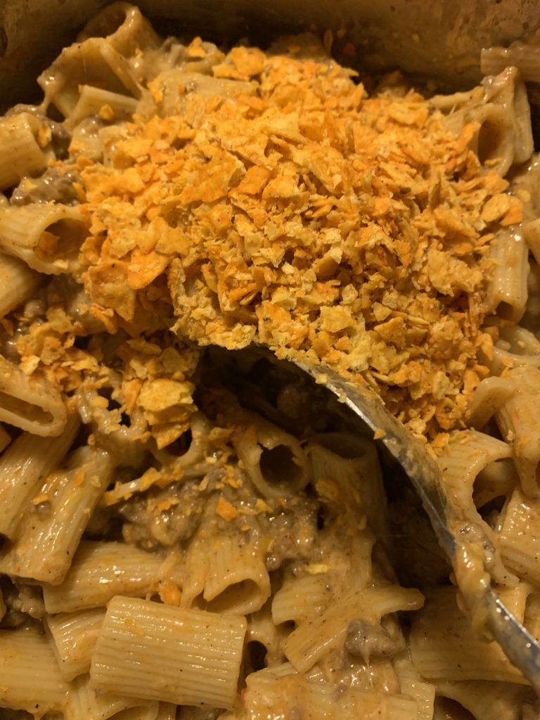 adding Dorito's nacho cheese chips to cheesy taco rigatoni