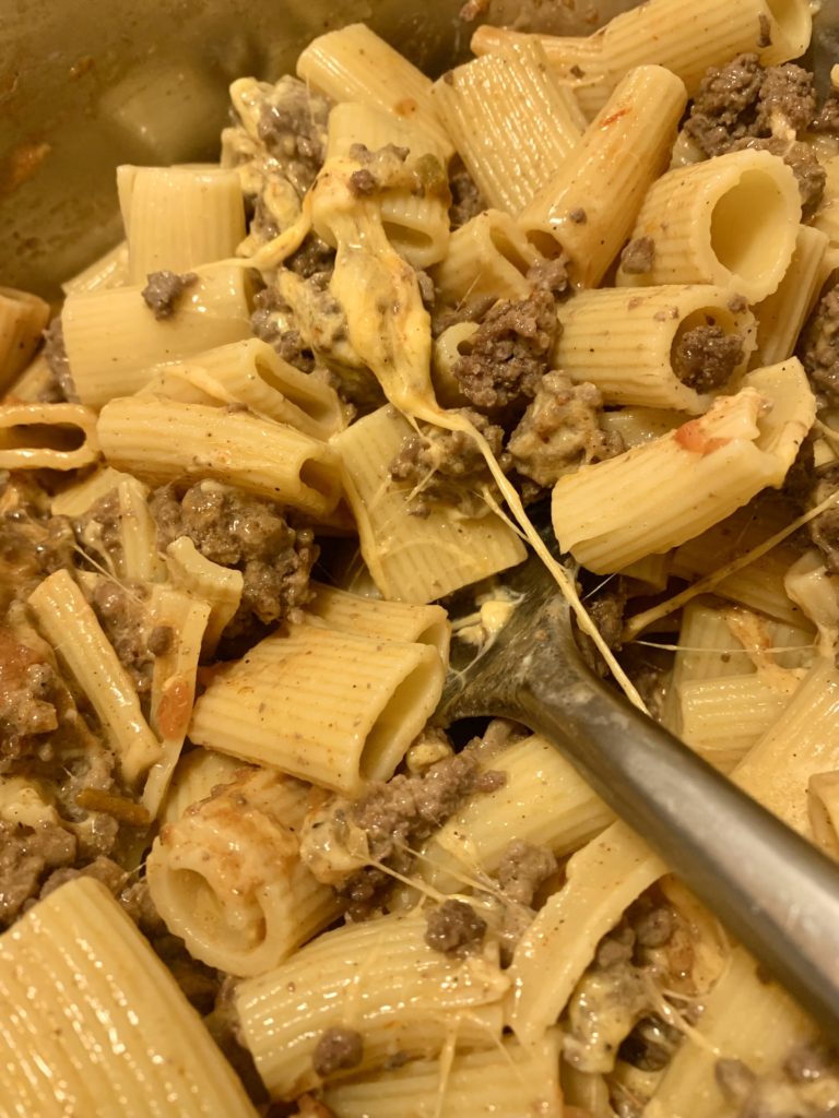 rigatoni being stirred with taco cheese sauce