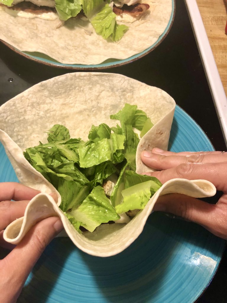 wrapping chicken Caesar wrap on light blue plate